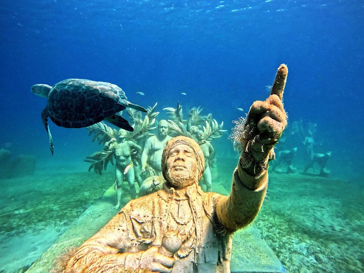 Turtle swimming of sculpture of man from St Maarten